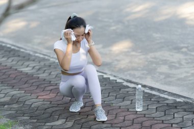 Güzel ve mutlu Asyalı kadın sabah egzersizinden sonra içmek için su şişesi tutuyor. Sabah koşusundan önce ısınıyor ve ısınıyor.