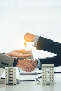 Ev ve konut kiralamayla ilgilenen emlakçılar, ev satın alma sözleşmesinin şartlarını görüşmek ve müşterilerden anahtarları ödemek için sözleşme imzalamalarını istemeye hazırlar..