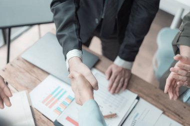 El ele tutuşan iş adamlarının elinde grafikler ve finansal tablolar, iş anlaşması konsepti, yakın plan görüntü.