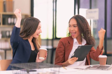 İki genç iş kadını laptoplarda çalışırken paneller hakkında konuşuyor, belgeler okuyor ve yeni bir projeyi tartışırken notlar yazıyorlar..