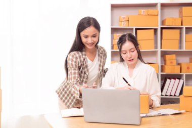 KOBİ sahibi, bayan girişimci müşterilere satılacak kutuları hazırlamak için sipariş numaralarını okuyun ve yazın ve online siparişleri kontrol edin. İş fikri.