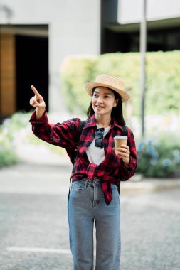 Sırt çantalı genç Asyalı bayan gezgin şehirde gündüz vakti şehir merkezi caddesinde yürüyor. tatil seyahat fikirleri