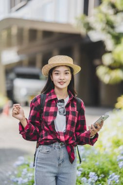 Sırt çantalı genç Asyalı bayan gezgin şehirde gündüz vakti şehir merkezi caddesinde yürüyor. tatil seyahat fikirleri