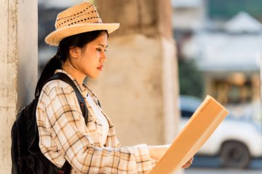 Sırt çantalı genç Asyalı bayan gezgin şehirde gündüz vakti şehir merkezi caddesinde yürüyor. tatil seyahat fikirleri