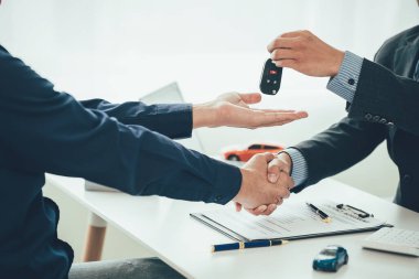 Bir araba satıcısı, elektrikli araba ruhsatı anlaşması için müşterisine teşekkür etmek için onunla tokalaşıyor..