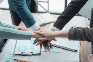 İş adamları el sıkışıyor, selamlaşıyor ve birlikte çalışıyor. Finansal grafikleri ve grafikleri olan belgeleri var. Beyin fırtınası yapıyor, yakın plan fotoğraf çekiyor.