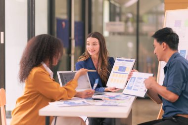 UI UX web tasarımcılarından oluşan bir ekip, modern bir konferans masasında bir projeyi görüşürken / tartışırken mobil bir yanıt veren web sitesi geliştirmek için birlikte çalışıyor. Beyin fırtınası.