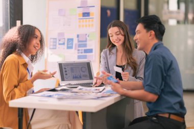UI UX web tasarımcılarından oluşan bir ekip, modern bir konferans masasında bir projeyi görüşürken / tartışırken mobil bir yanıt veren web sitesi geliştirmek için birlikte çalışıyor. Beyin fırtınası.
