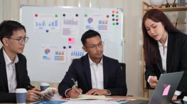 Bir grup iş adamı, finansal stratejiler hakkında konferans odasında dizüstü bilgisayarlarla beyin fırtınası ve pazarlama ve pazarlama analitik dokümanlarını tartışıyor..