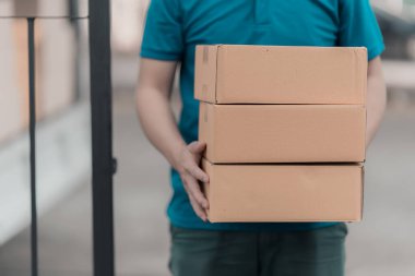 Asyalı erkek kurye elinde sarı kutu, teslimat konsepti.