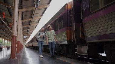 İki erkek ve kadın turist, turizm için trenle seyahat etmeye hazırlanıyor. 4K yavaş çekim videosu.