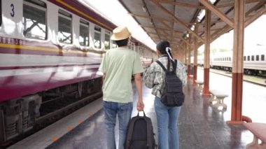 İki erkek ve kadın turist, turizm için trenle seyahat etmeye hazırlanıyor. 4K yavaş çekim videosu.