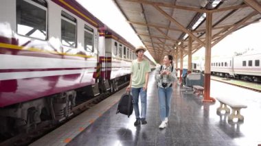 İki erkek ve kadın turist, turizm için trenle seyahat etmeye hazırlanıyor. 4K yavaş çekim videosu.