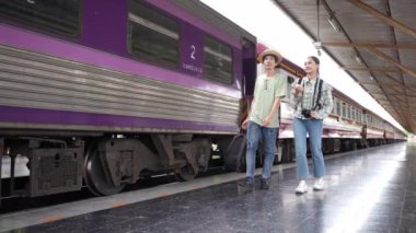İki erkek ve kadın turist, turizm için trenle seyahat etmeye hazırlanıyor. 4K yavaş çekim videosu.