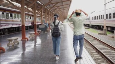 İki erkek ve kadın turist, turizm için trenle seyahat etmeye hazırlanıyor. 4K yavaş çekim videosu.