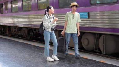 İki erkek ve kadın turist, turizm için trenle seyahat etmeye hazırlanıyor. 4K yavaş çekim videosu.