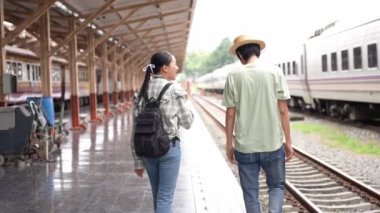 İki erkek ve kadın turist, turizm için trenle seyahat etmeye hazırlanıyor. 4K yavaş çekim videosu.