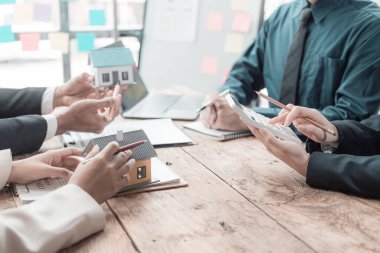 İş adamları gayrimenkul hakkında konuşmak için toplanıyor. Emlak işinde takım çalışması. Müşterilere tanıtmak için satış yaklaşımı analiz ediliyor. Yakın plan..