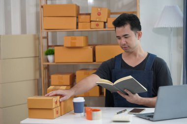 Küçük işletme sahibi müşteriye göndermek için paket kutusuna akıllı telefon ve yazma adresi kullanmaya başladı. Web sitesi ve sosyal medyada ekomünikasyon işi yapan işadamı kavramı.