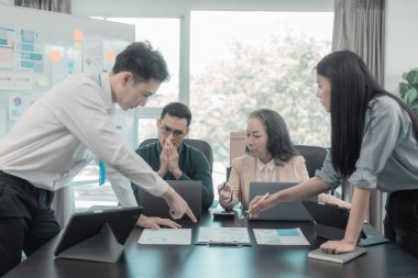 İş sunumu ya da seminer için Asyalı iş adamları konferans odasında. Belgelerde mali ya da pazarlama rakamları, grafikleri ve grafikleri var. Şirket hisselerini analiz etmek için bir laptop var..
