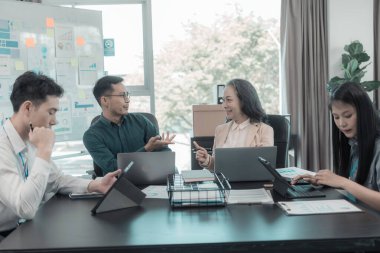 İş sunumu ya da seminer için Asyalı iş adamları konferans odasında. Belgelerde mali ya da pazarlama rakamları, grafikleri ve grafikleri var. Şirket hisselerini analiz etmek için bir laptop var..