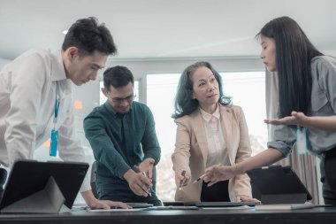 İş sunumu ya da seminer için Asyalı iş adamları konferans odasında. Belgelerde mali ya da pazarlama rakamları, grafikleri ve grafikleri var. Şirket hisselerini analiz etmek için bir laptop var..