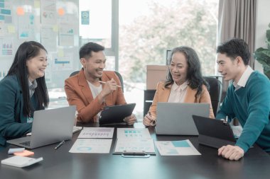 İş sunumu ya da seminer için Asyalı iş adamları konferans odasında. Belgelerde mali ya da pazarlama rakamları, grafikleri ve grafikleri var. Şirket hisselerini analiz etmek için bir laptop var..