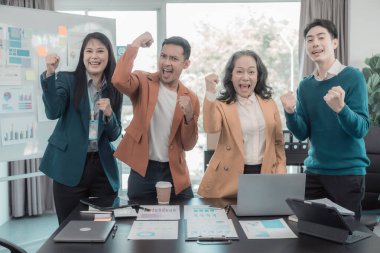 Çeşitli iş adamları bir konferans masasında toplanarak bir iş zaferini, iyi bir satış sonucunu ve finansal bir hedefe ulaşmayı kutluyor..