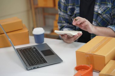 Küçük işletme sahibi akıllı telefon kullanarak karton kutulara adresler yazarak ve paket paketleyerek işe başlıyor. Müşterilere paket teslimatı yapan küçük bir işletme. KOBİ girişimcisi.