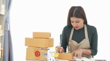 Fatura kutuları üzerinde çalışan ve kutuları hazırlamak, müşterilere satmak için online siparişleri kontrol eden kadın KOBİ işletme sahibi girişimci. Çevrimiçi KOBİ iş konsepti, küçük işletme başlangıcı.