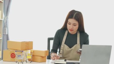 Fatura kutuları üzerinde çalışan ve kutuları hazırlamak, müşterilere satmak için online siparişleri kontrol eden kadın KOBİ işletme sahibi girişimci. Çevrimiçi KOBİ iş konsepti, küçük işletme başlangıcı.