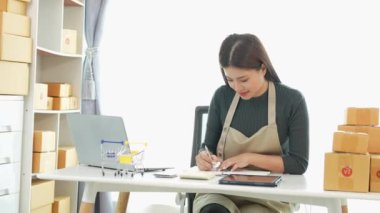 Fatura kutuları üzerinde çalışan ve kutuları hazırlamak, müşterilere satmak için online siparişleri kontrol eden kadın KOBİ işletme sahibi girişimci. Çevrimiçi KOBİ iş konsepti, küçük işletme başlangıcı.