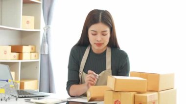 Fatura kutuları üzerinde çalışan ve kutuları hazırlamak, müşterilere satmak için online siparişleri kontrol eden kadın KOBİ işletme sahibi girişimci. Çevrimiçi KOBİ iş konsepti, küçük işletme başlangıcı.