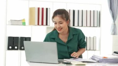 Diz üstü bilgisayarı kullanarak vergi, muhasebe, istatistik ve analiz araştırması yapan Asyalı iş kadını ve masada hesap makinesi ile birlikte belgeler, planlama ve mali raporları analiz ediyor..