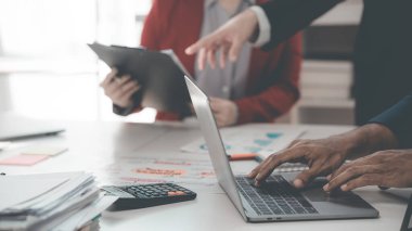 Takım çalışmalarının başarısını gösteren çizelge ve grafikleri tartışan iş ekibi iş stratejisi hakkındaki finansal verileri analiz ediyor. Kapat..