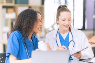 İki kadın bilimadamı, kan örnekleri ve test tüpleriyle bir laboratuvarda çalışıyorlar. Araştırmalarını sürdürürken, çözeltileri damlalardan gelen pipetlerle dolduruyorlar..