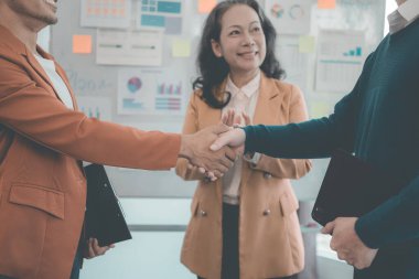 İş adamları iş görüşmesi yaparken el sıkışıyorlar. İş stratejisi konusunda arabuluculuk ve anlaşmazlıklar için depo Toplantıda performans grafikleri ve grafikleri ele alındı.