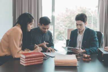 Avukatlar müşterilerle modern bir ofiste müşterilerle görüşür, müşterilerle görüşür. Avukatlar müşterilerine masalarında çalışırken aktif olarak danışmanlık yaparlar..