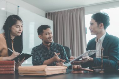 Avukatlar müşterilerle modern bir ofiste müşterilerle görüşür, müşterilerle görüşür. Avukatlar müşterilerine masalarında çalışırken aktif olarak danışmanlık yaparlar..