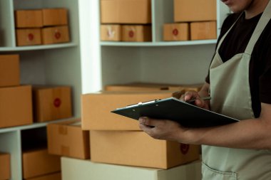 KOBİ işi için evden paket siparişi vermek için dizüstü bilgisayar ve kutularla çalışan Asyalı genç girişimcinin girişimcisi