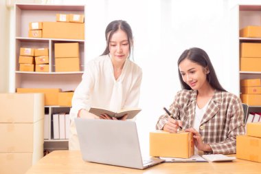 Küçük işletme girişimi, KME sahibi, çevrimiçi siparişleri kontrol eden Asyalı kadın, evde ürün satmak, kutular ve dizüstü bilgisayarlarla çalışmak, serbest çalışan