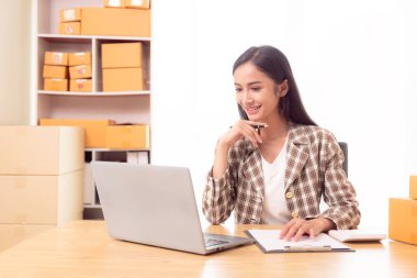 Küçük işletme girişimi, KME sahibi, çevrimiçi siparişleri kontrol eden Asyalı kadın, evde ürün satmak, kutular ve dizüstü bilgisayarlarla çalışmak, serbest çalışan