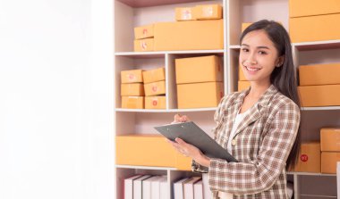 Küçük işletme girişimi, KME sahibi, çevrimiçi siparişleri kontrol eden Asyalı kadın, evde ürün satmak, kutular ve dizüstü bilgisayarlarla çalışmak, serbest çalışan