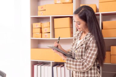 Küçük işletme girişimi, KME sahibi, çevrimiçi siparişleri kontrol eden Asyalı kadın, evde ürün satmak, kutular ve dizüstü bilgisayarlarla çalışmak, serbest çalışan