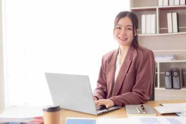 Dizüstü bilgisayar kullanan kadın finansör bir finans şirketi için rapor hazırlar, vergi giderlerini hesaplamak ve finansal belgeleri analiz etmek için ofiste bir masaya oturur..