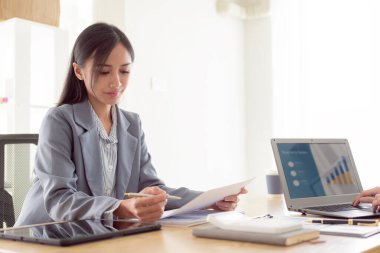 Dizüstü bilgisayar kullanan kadın finansör bir finans şirketi için rapor hazırlar, vergi giderlerini hesaplamak ve finansal belgeleri analiz etmek için ofiste bir masaya oturur..