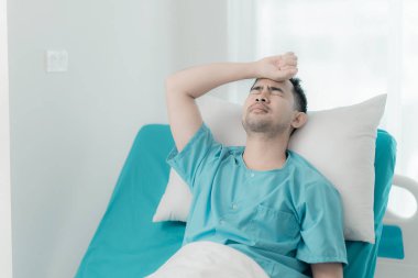 Ciddi derecede hasta bir adam hastane yatağında tek başına yatıyor. Hasta başarılı bir ameliyattan sonra iyileşiyor. Hasta erkek hasta hastanede özel koğuşta yatıyor.