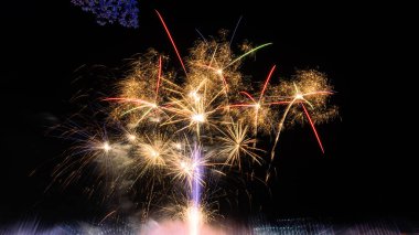 Şehrin üzerinde büyük havai fişekler, yeni yıl partisi arka planı, yeni yıl, koyu mavi gökyüzünde güzel renklerle uzun havai fişekler..