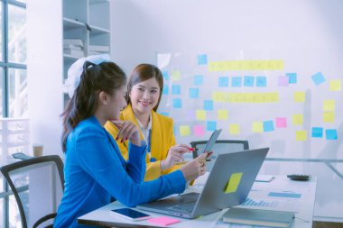 Asyalı iş kadınlarından oluşan bir grup başarılı takım çalışmalarını gösteren grafikler ve grafikler, şirket büyüme hedefleri, bilgisayar ekranlarındaki sunumlar hakkında görüştü.