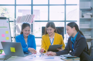 Asyalı iş kadınlarından oluşan bir grup başarılı takım çalışmalarını gösteren grafikler ve grafikler, şirket büyüme hedefleri, bilgisayar ekranlarındaki sunumlar hakkında görüştü.